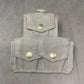 Two gray fabric pouches with buttons on a gray surface