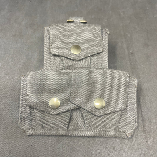 Two gray fabric pouches with buttons on a gray surface