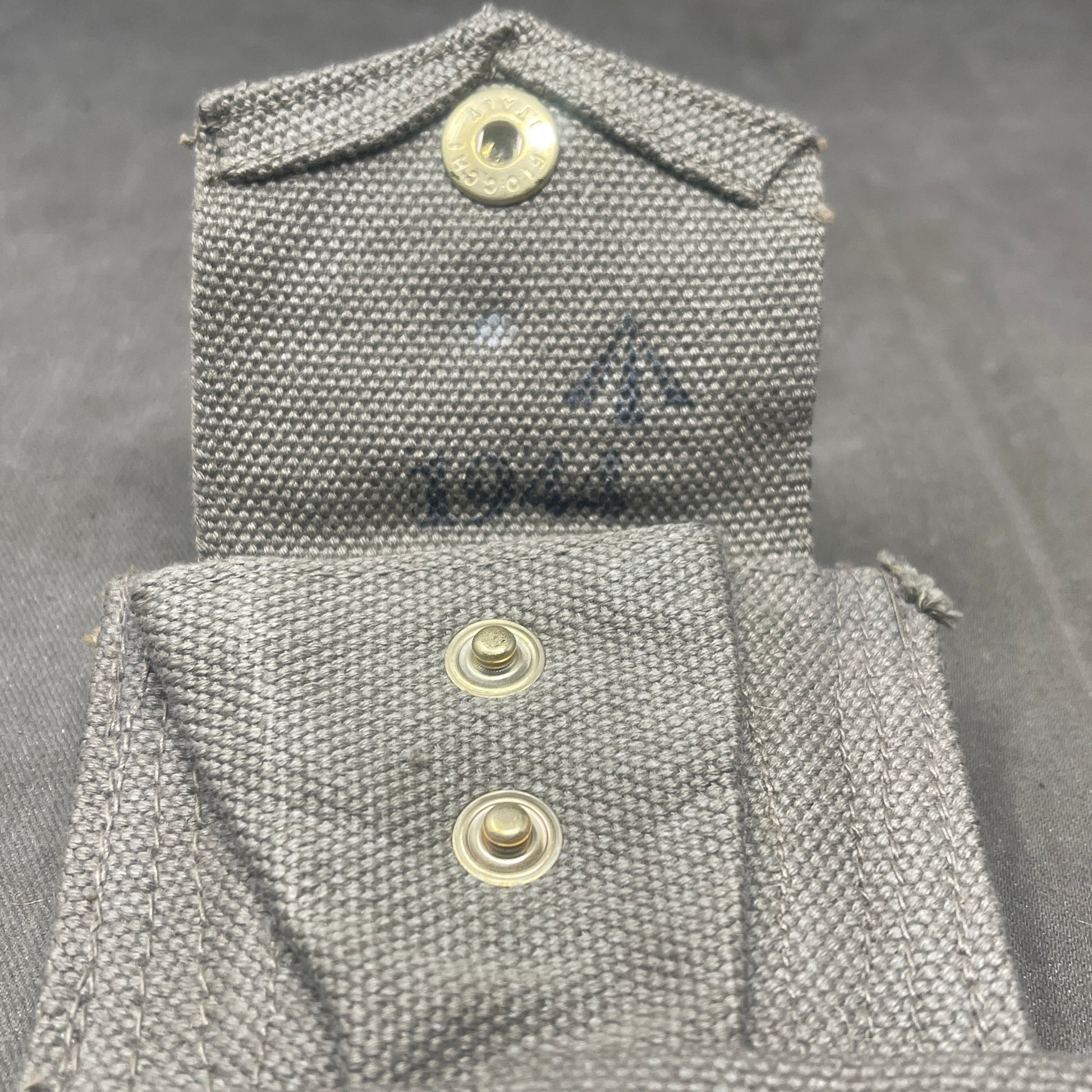 Close-up of a gray fabric pocket with buttons on a dark background