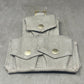 Folded fabric pouch with metal buttons on a gray background