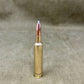 Bronze-colored rifle cartridge on a textured beige background