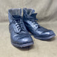 Pair of worn blue leather boots on a beige fabric background