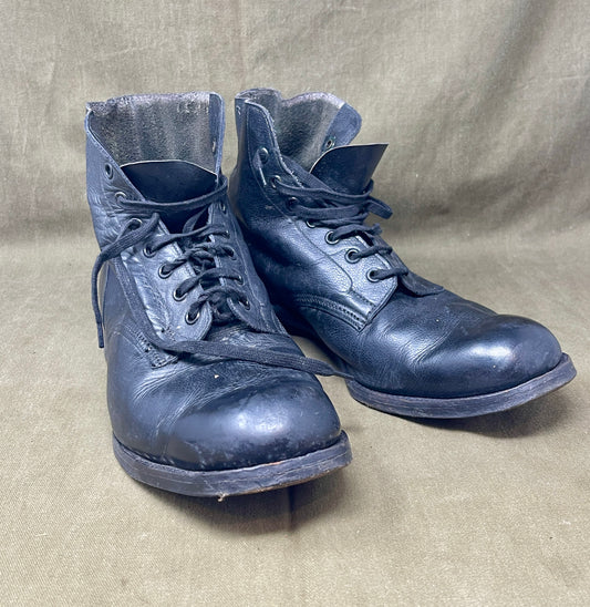 Pair of worn blue leather boots on a beige fabric background