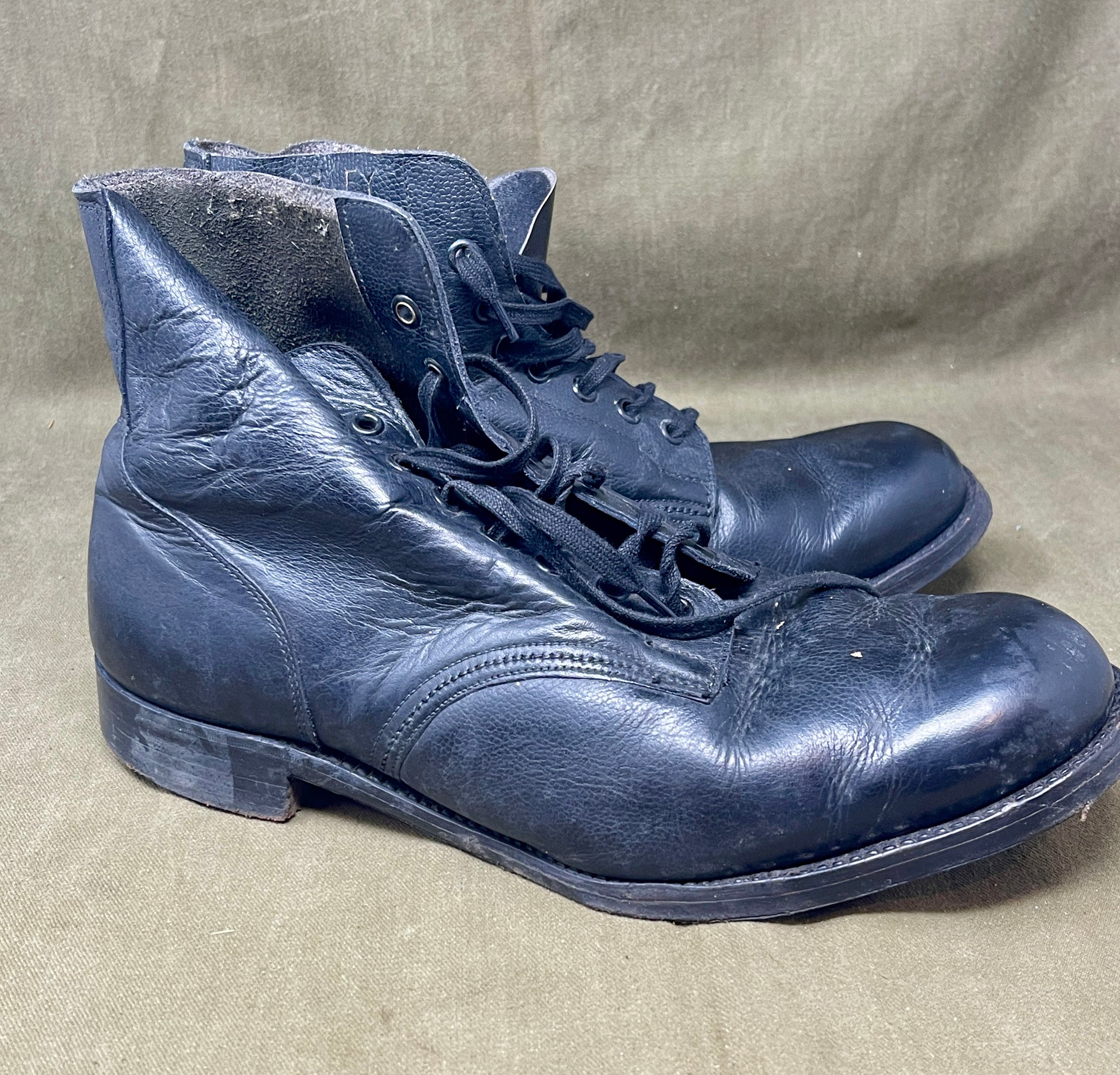 Pair of worn blue leather boots on a beige background