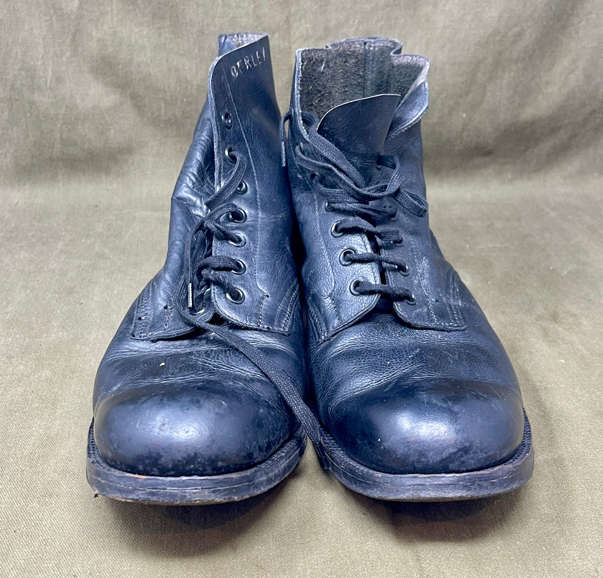 Pair of worn blue boots on a beige fabric background