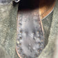 Close-up of a shoe sole with 'B.S.C. & Co.' and '1954' embossed on it, set against a textured green background.