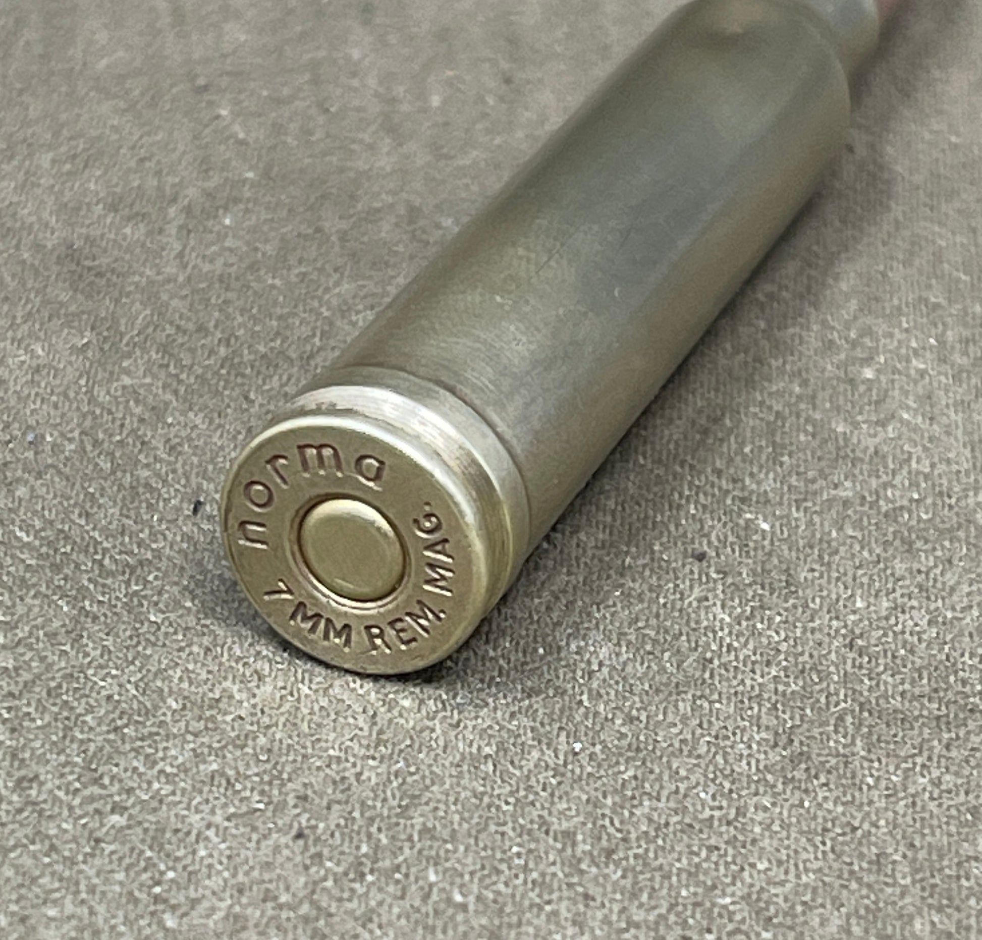 Close-up of a metal cylindrical object with 'Norma' branding on a gray surface