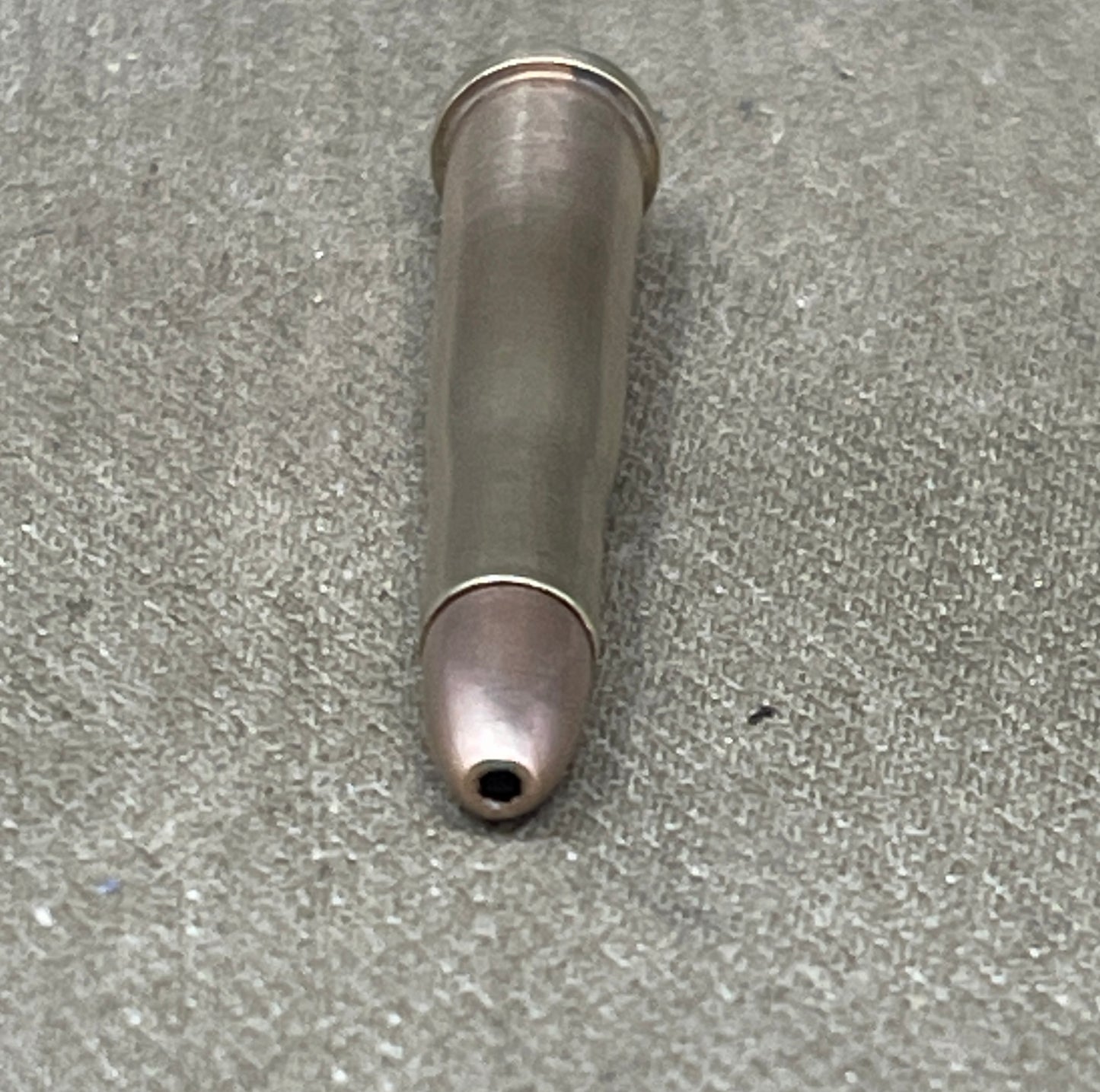 Metallic bullet casing on a gray concrete surface