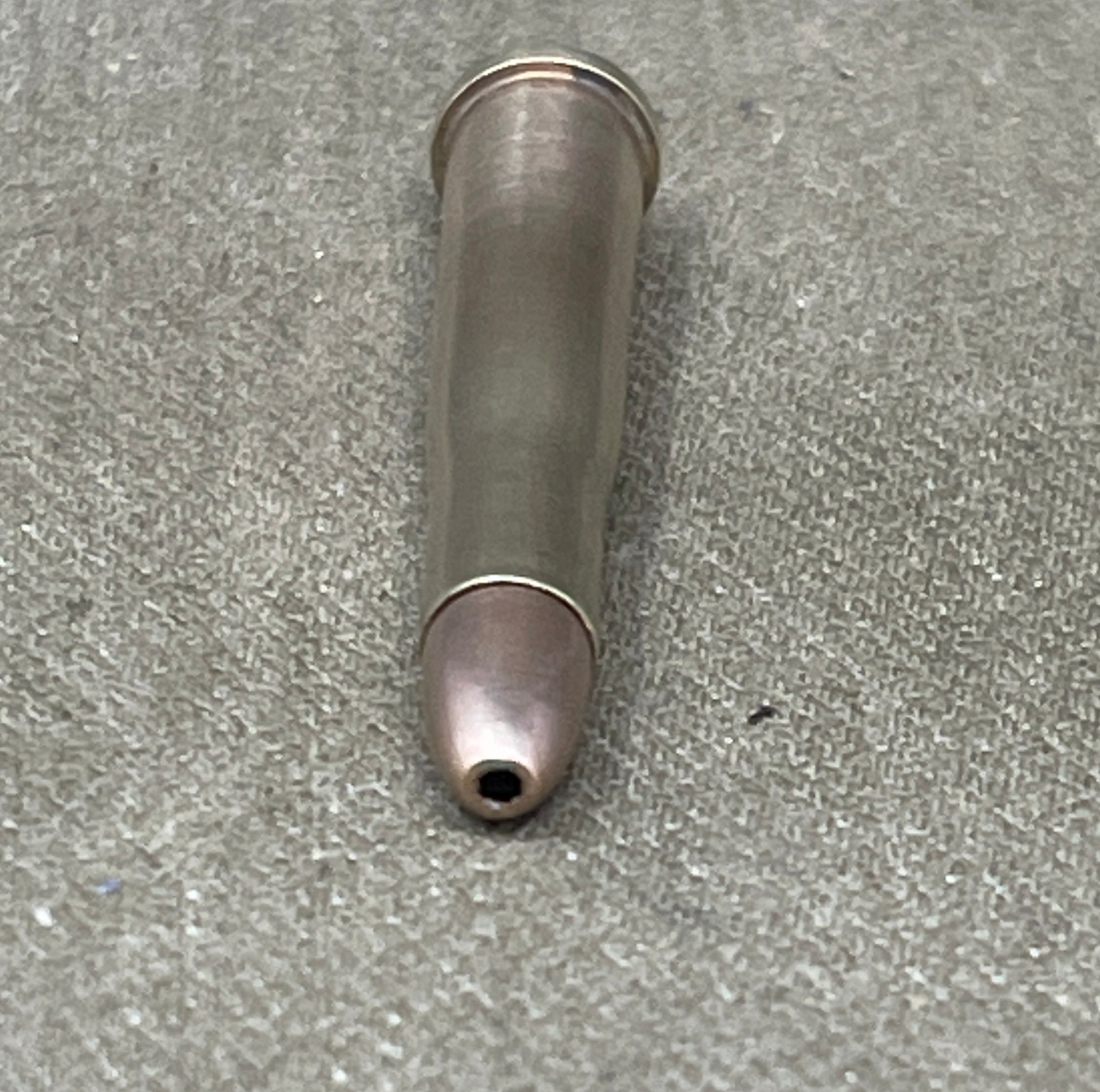 Metallic bullet casing on a gray concrete surface