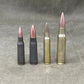 Four different types of rifle ammunition on a gray surface
