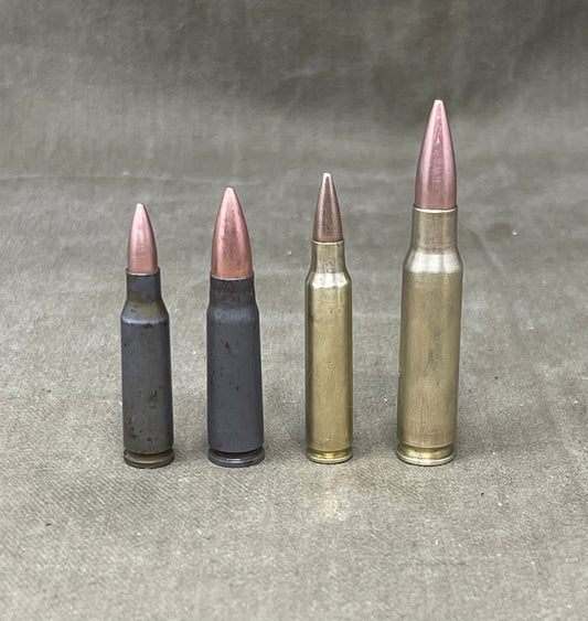 Four different types of rifle ammunition on a gray surface