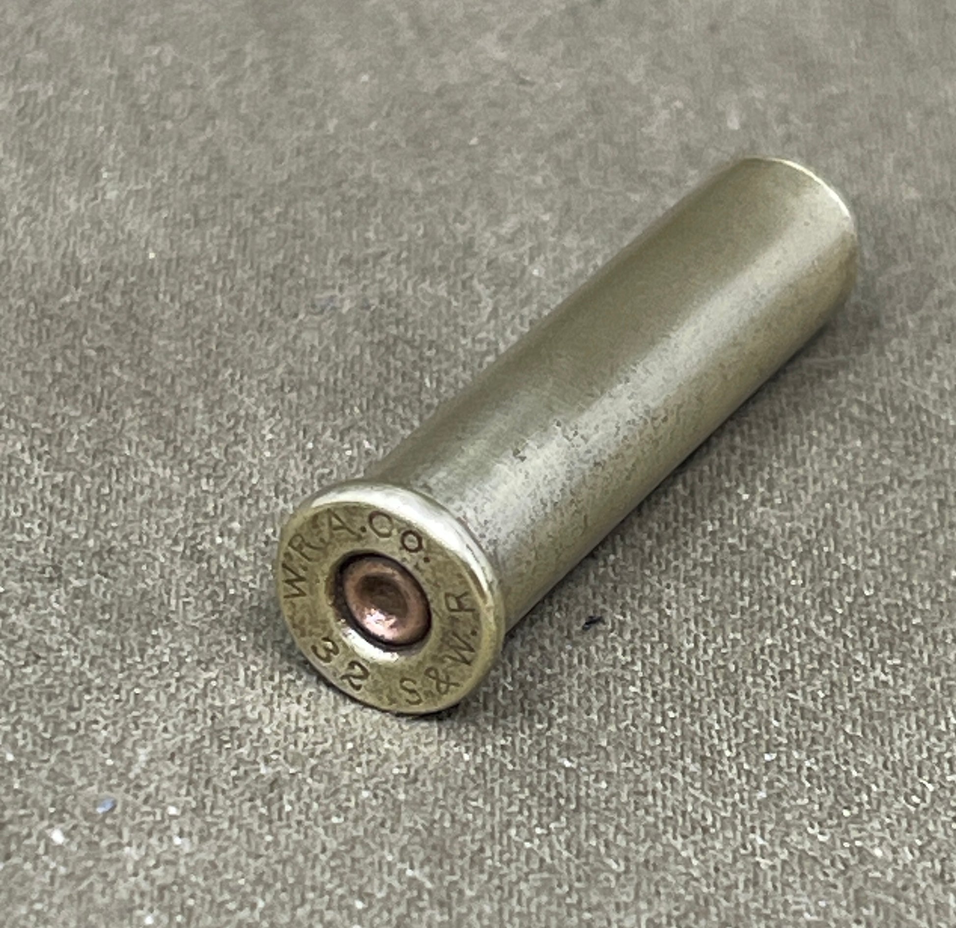 Metallic cartridge casing on a gray surface
