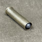Metallic cylindrical object with a dark gray sphere inside on a textured beige surface