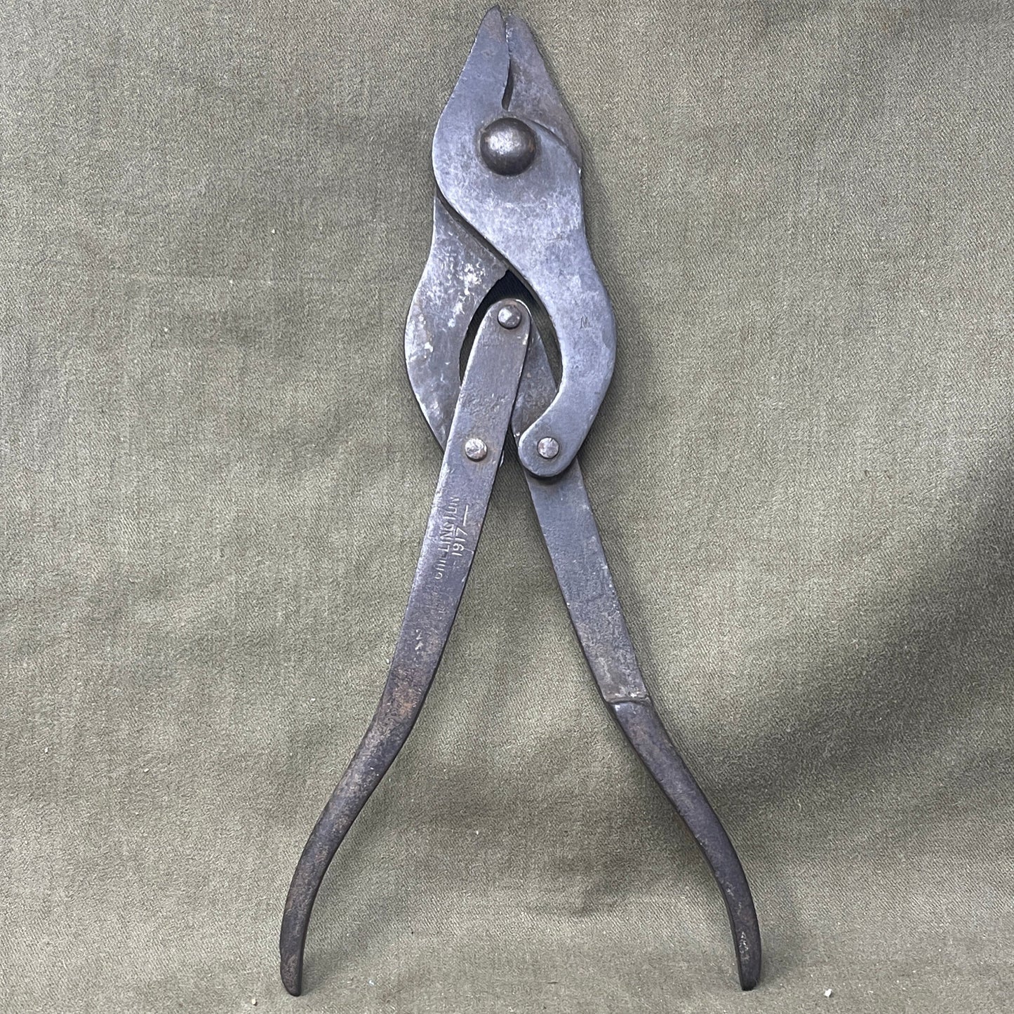 Original WWI British Wire Cutters, dated 1917 and made by Chillington, are durable steel tools with wooden handles, designed for cutting barbed wire in trench warfare. Essential for soldiers, these cutters reflect practical WWI engineering and are highly valued by collectors for their historical significance