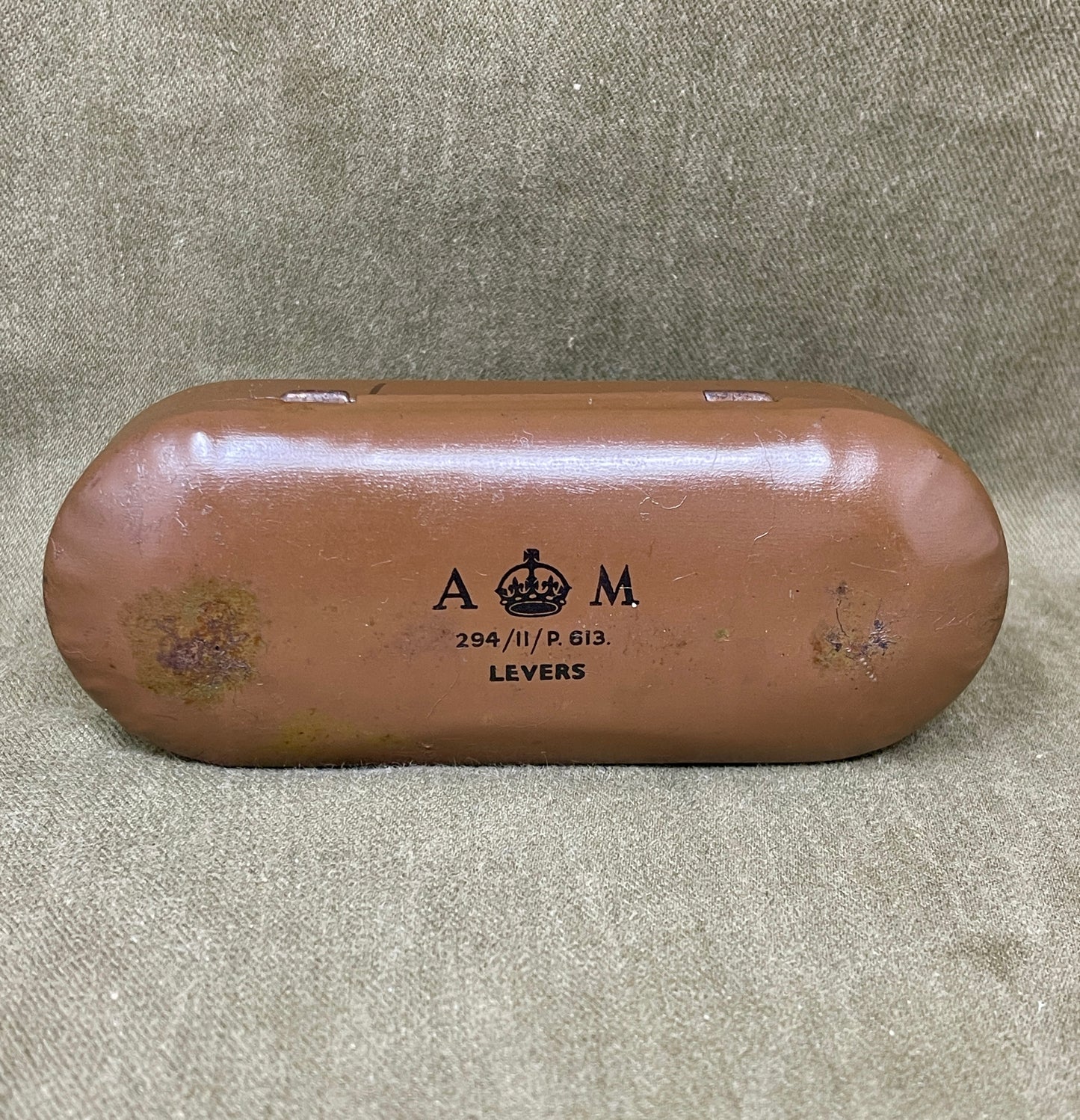 Brown metal object with 'A & M' branding on a textured gray background