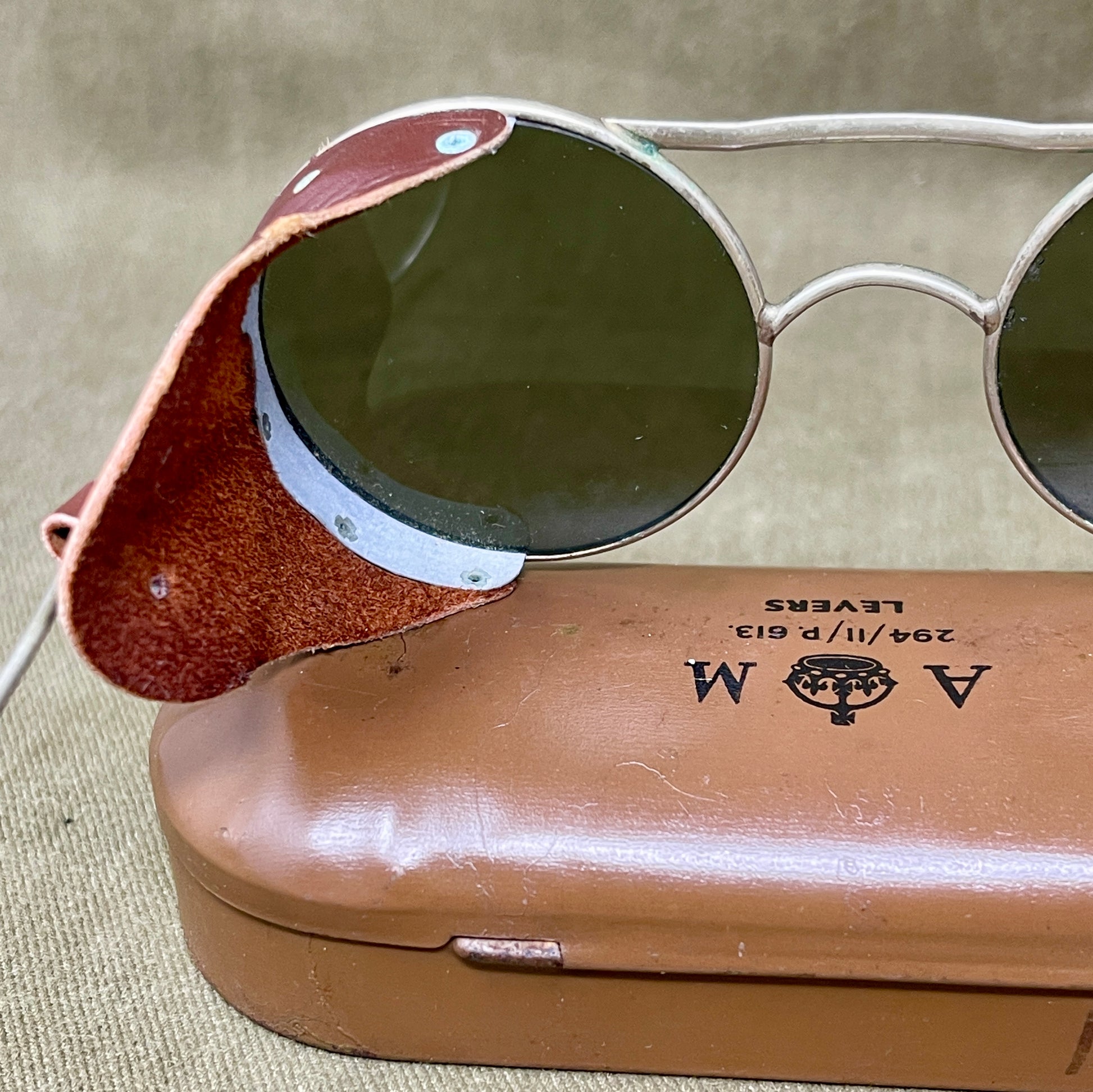 Round sunglasses with a brown case on a beige fabric background