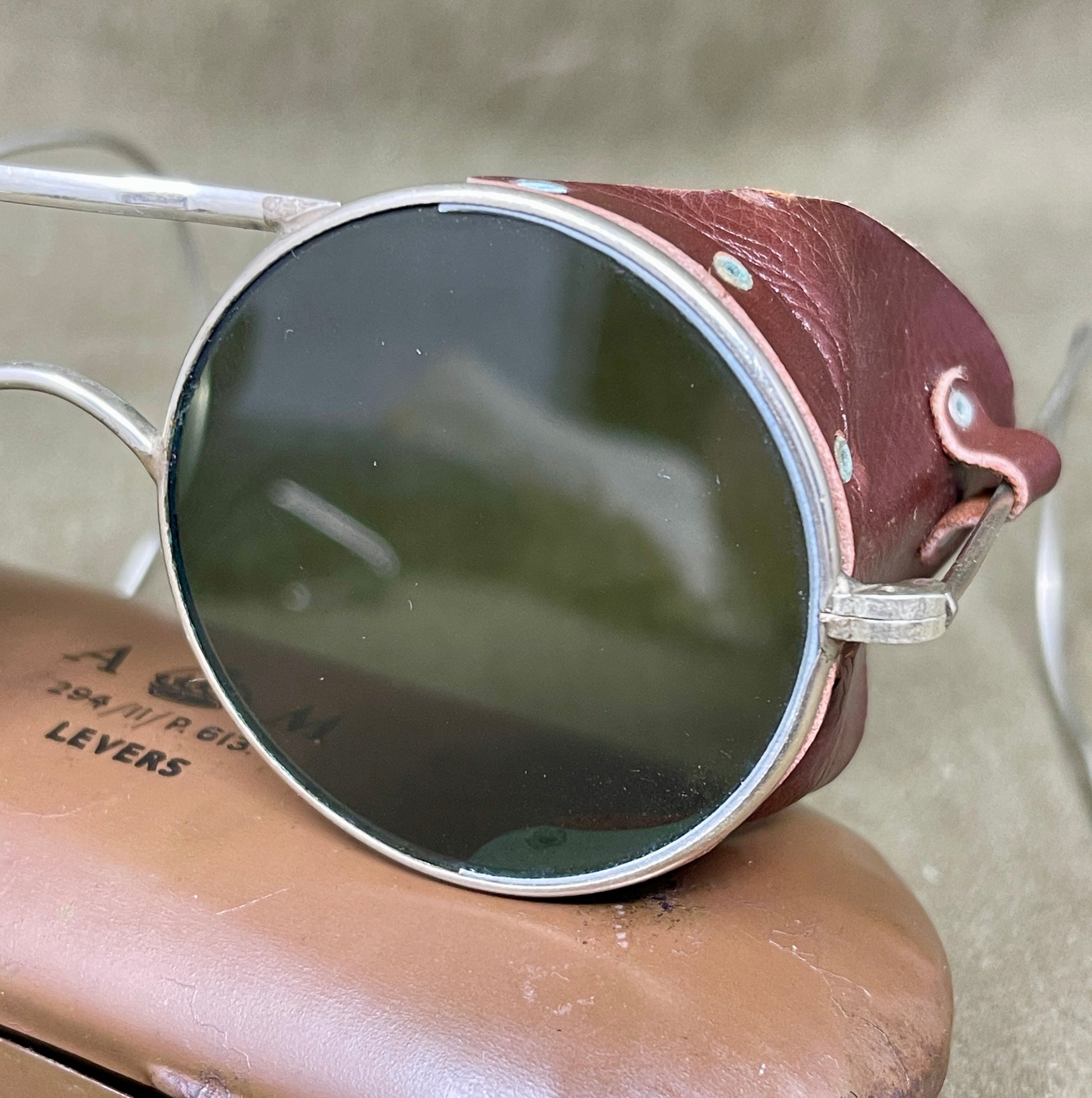 Round sunglasses with brown frame and reflective lenses on a beige surface