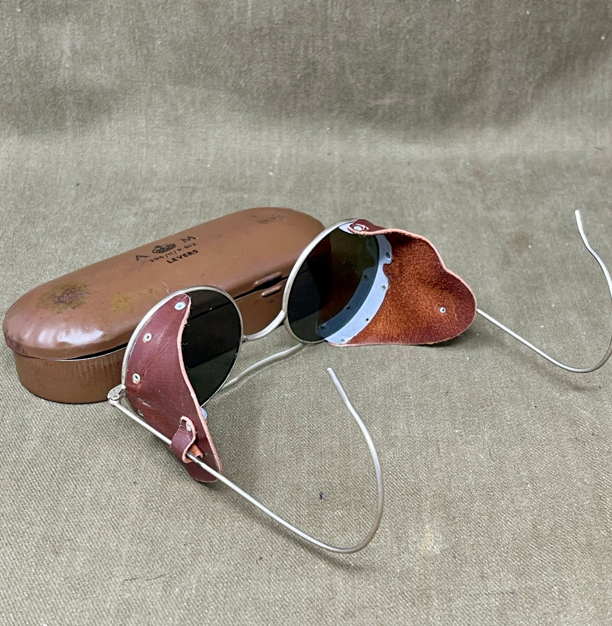 Vintage sunglasses with brown leather case on a textured surface